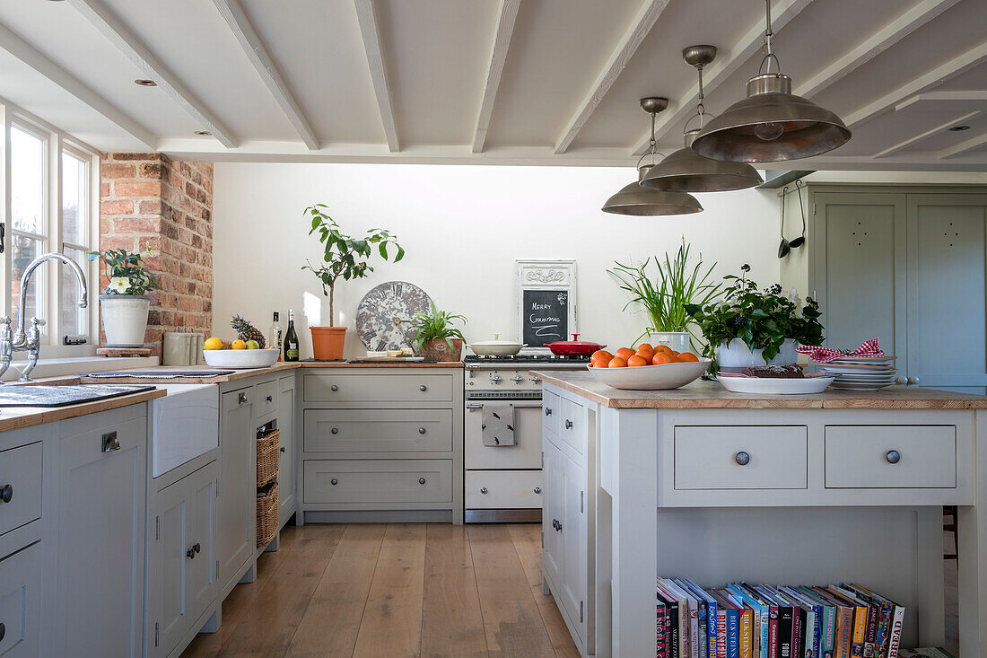 Metal pendant shades above island unit in grey fitted West Sussex farmhouse kitchen UK