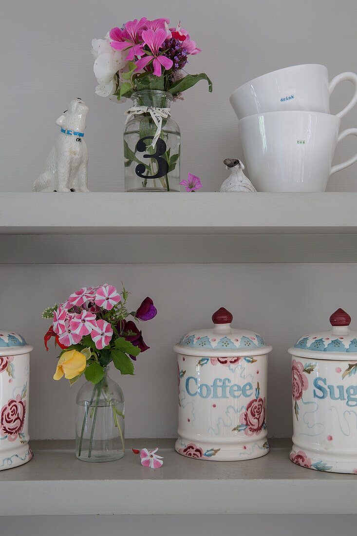 Cut flowers and chinaware with dog ornament on shelves in Alford kitchen Surrey UK