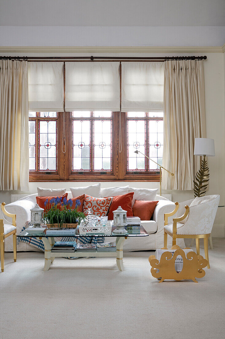 Carved magazine rack with white sofa at window with gilt chairs in West Sussex townhouse UK