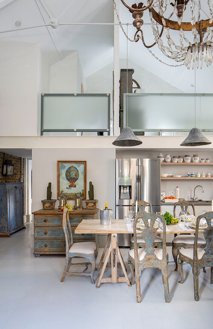 Dining table below frosted glass mezzanine in open plan South London schoolhouse conversion UK