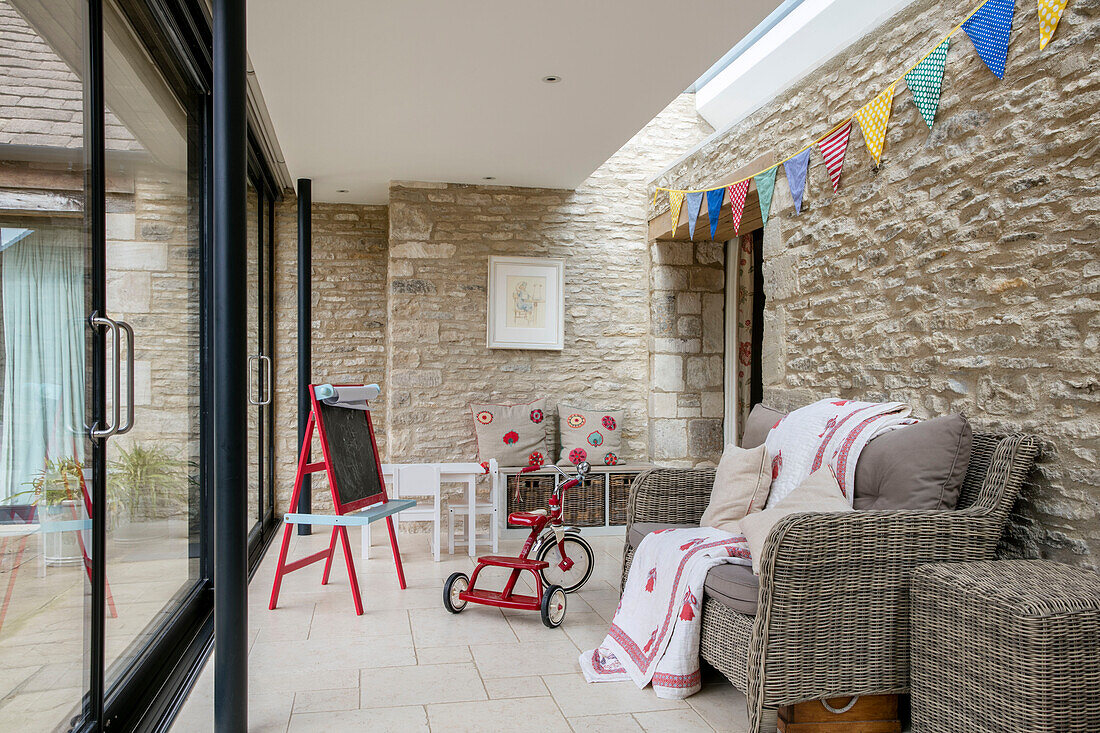 Chalkboard and tricycle with two seater sofa and bunting in Gloucestershire barn conversion UK