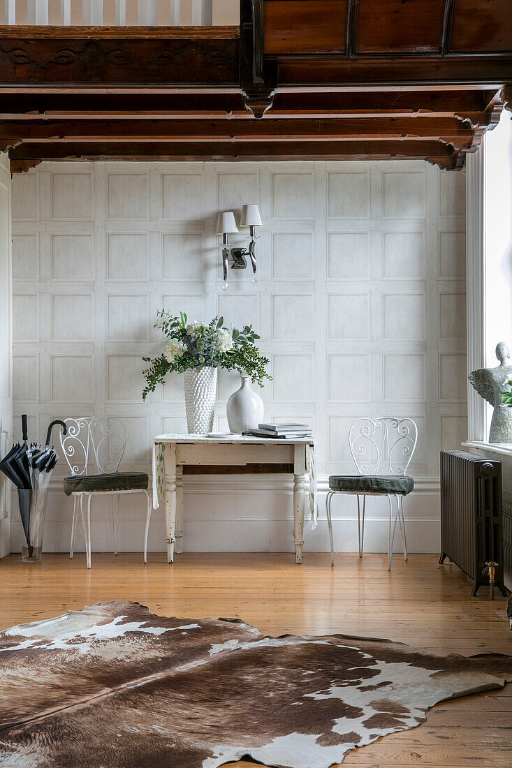 Table and chairs with animal skin rug in large entrance hall of detached Kent home UK