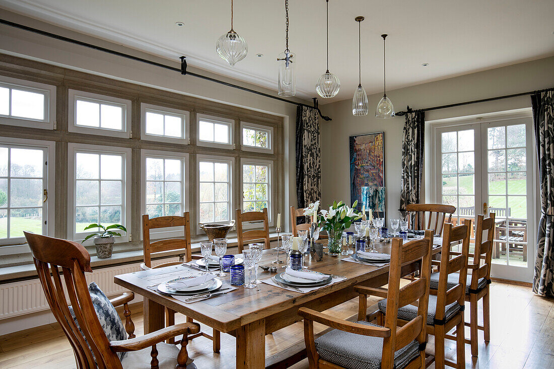 Esstisch und Stühle aus Holz mit Glaspendelleuchten in einem Haus in West Sussex, Großbritannien