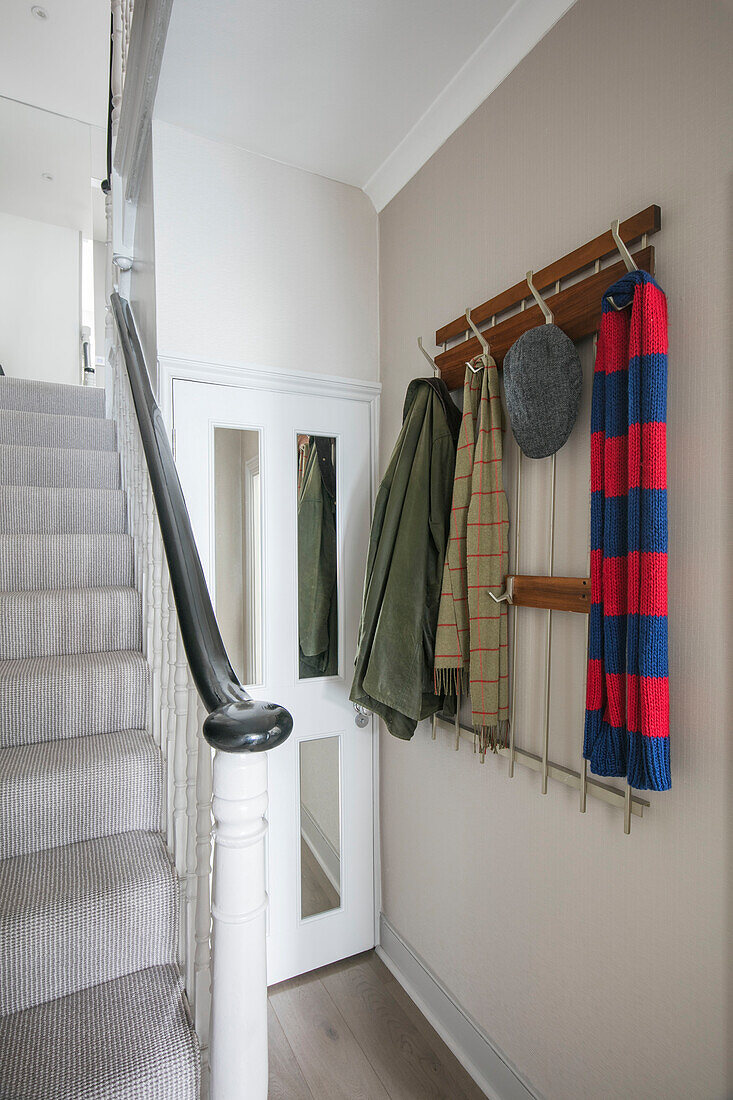 Hat coat and scarf hanging staircase hallway of London home UK