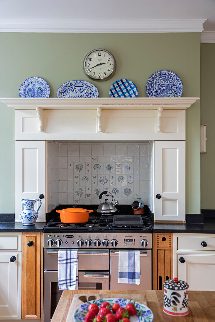 Pans on hob with plates on shelf above recessed stove in Arts and Crafts kitchen Sevenoaks Kent UK