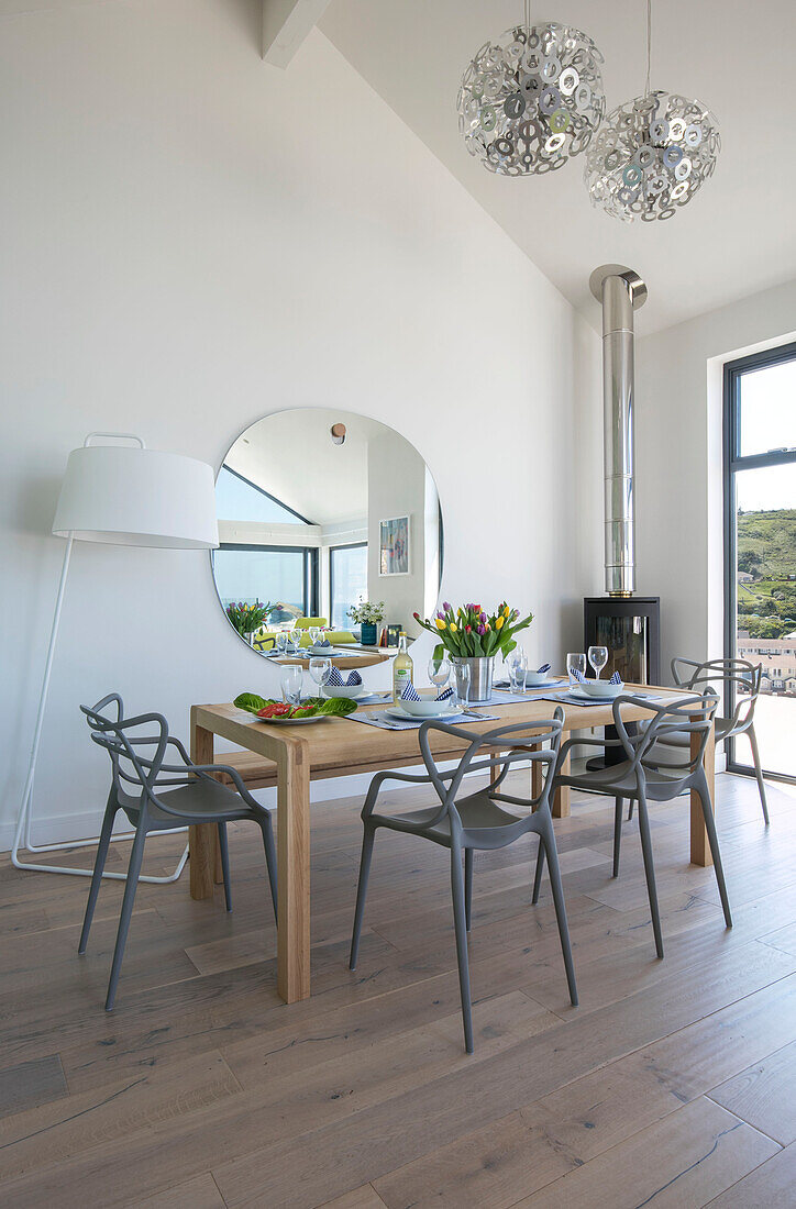 Grey dining chairs at table with large lamp and mirror in newbuild Cornwall UK