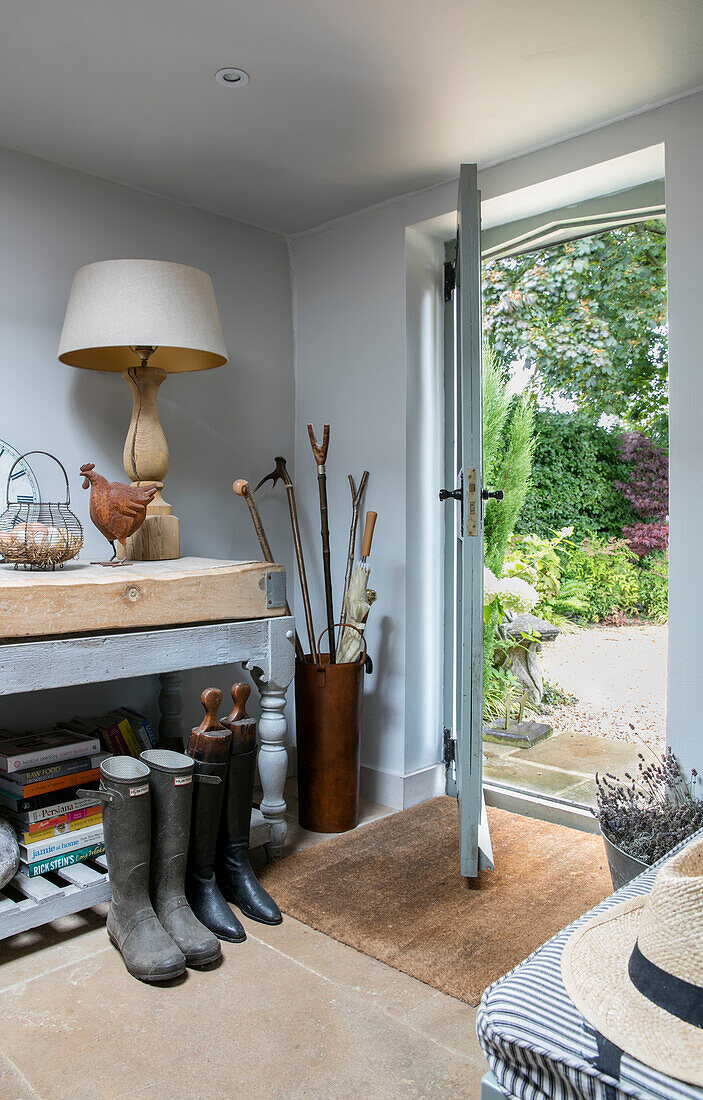 Cream lamp and umbrella stand with wellington boots with hall table in Oxfordshire home UK