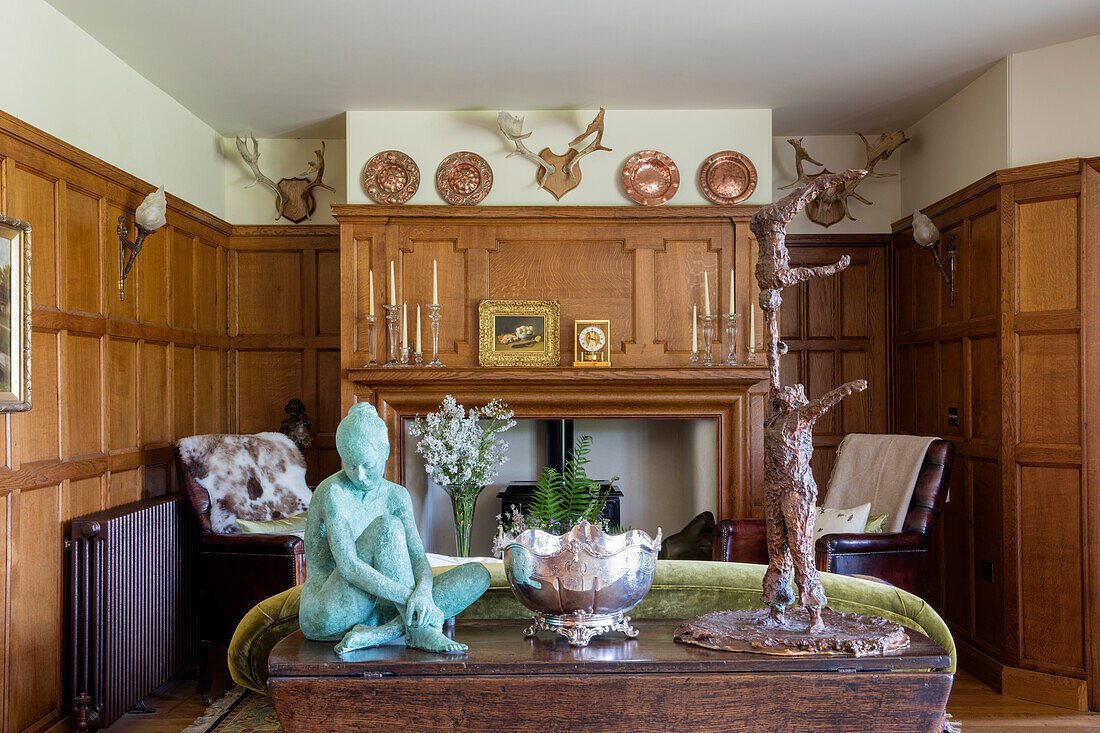 Sculptures on drop-leaf table in panelled living room of Devon home UK