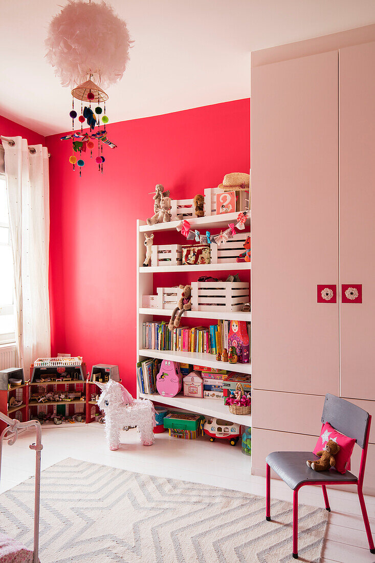 Wardrobe and chair with toys and books on shelves in playroom of London home UK