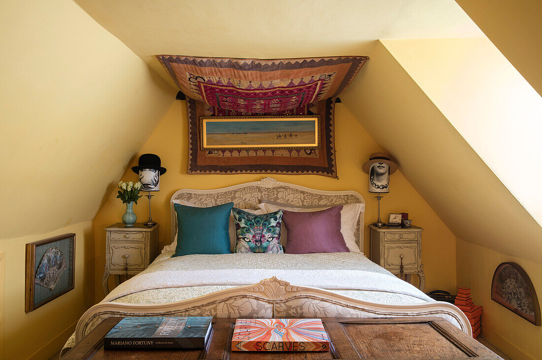 Wall hangings in attic bedroom with hat stands in Sussex home