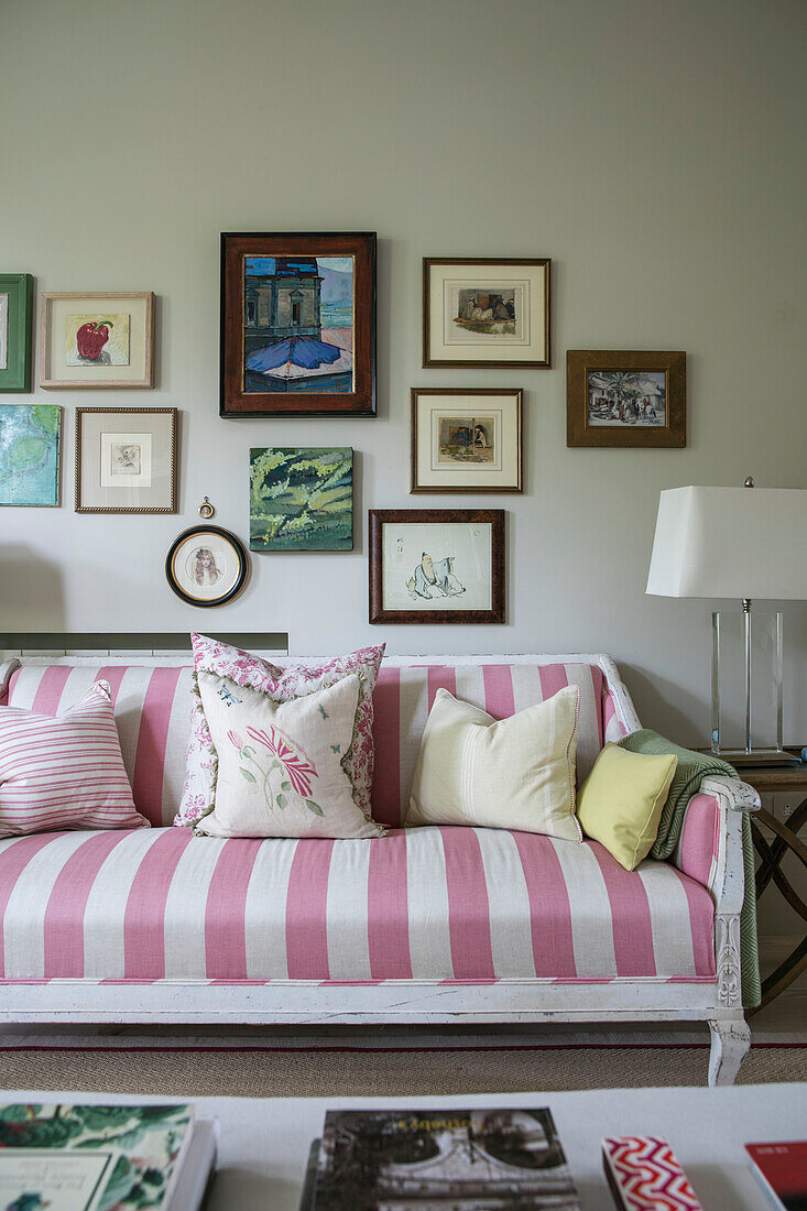 Rosa und weiß gestreiftes Sofa mit Bilderwand in einem Londoner Wohnzimmer UK