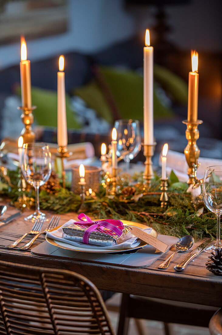 Weihnachtsgeschenk auf einem Gedeck mit brennenden Kerzen und Laub in einem Landhaus in Norfolk England UK
