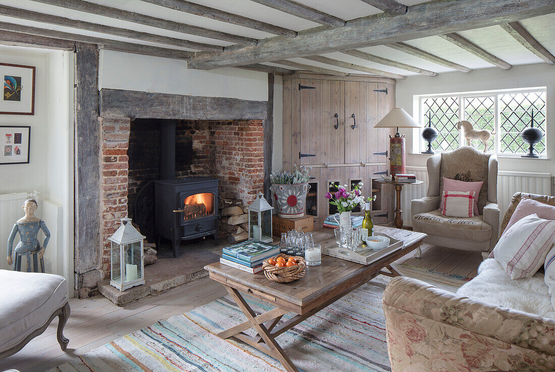 Steinkamin aus der Zeit um 1600 mit französischem Couchtisch und hölzernem Eckschrank in einem Bauernhaus in Surrey, Großbritannien