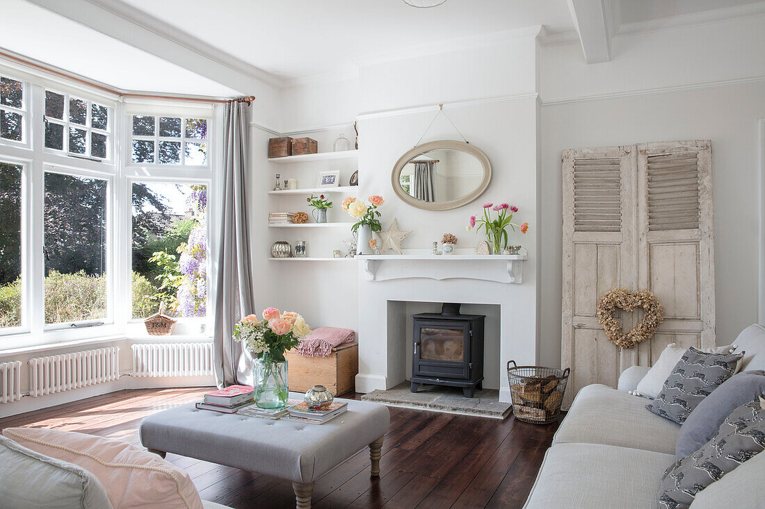 Schnittblumen in einem sonnenbeschienenen pastellgrauen Wohnzimmer mit originalem Dielenboden in einem unter Denkmalschutz stehenden Landhaus in Hertfordshire, UK