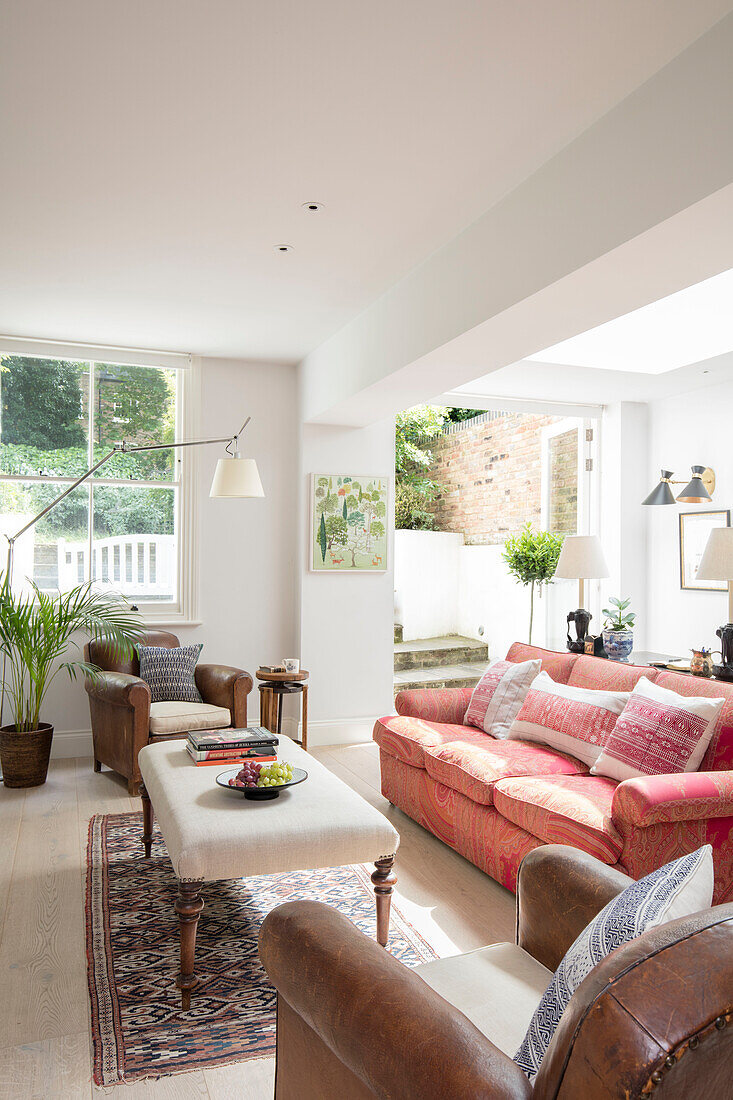 Sofa with ottoman with open door to garden terrace in basement extension of North London apartment UK