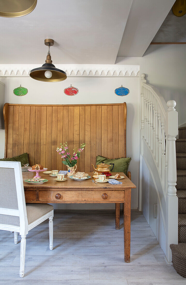 Wooden church pew and table set for afternoon tea in 1840s Cotswolds cottage Oxfordshire UK