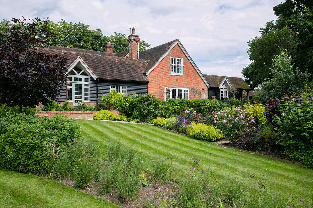 Summer garden and lawn of 1900s former coach house West Sussex England UK