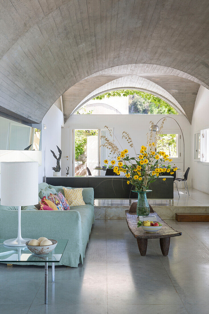Flowers on coffee table with light green sofa in vaulted Italian villa on Amalfi coast