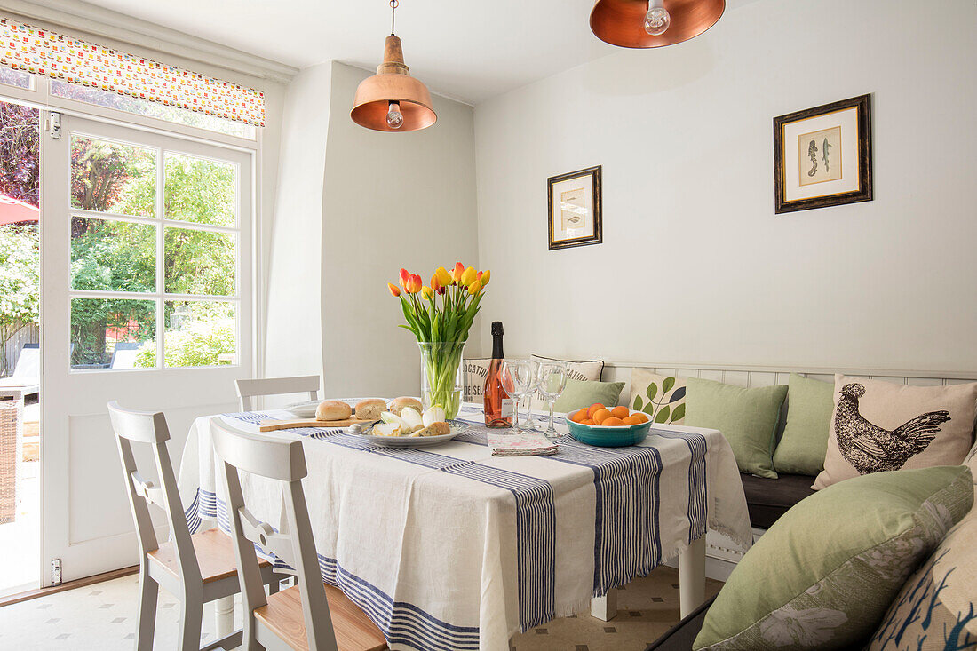 Tulpen auf einem Tisch mit Hühnerkissen und Kupferanhängern in einem Cottage in Wiltshire, UK