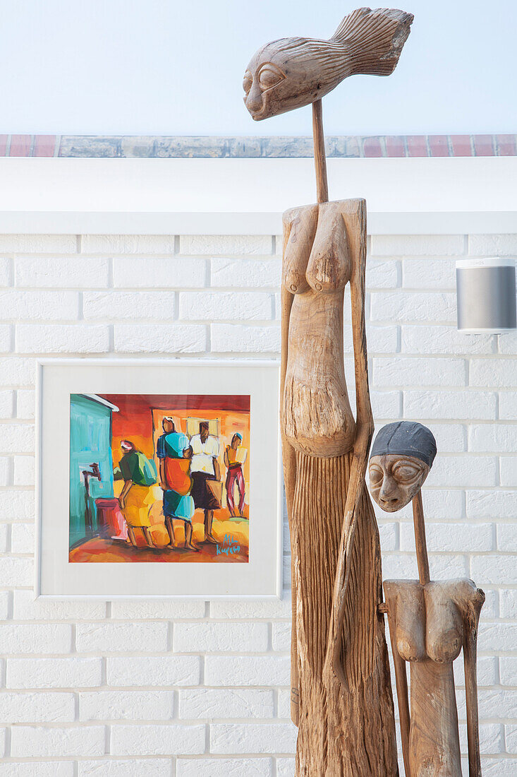 Two ethnic sculptures with modern artwork set against whitewashed wall in London home UK