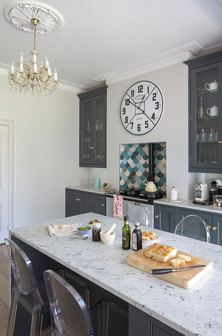 Breadboard on kitchen island with large clock and cabinets in Downpipe Victorian villa Tunbridge Wells Kent UK