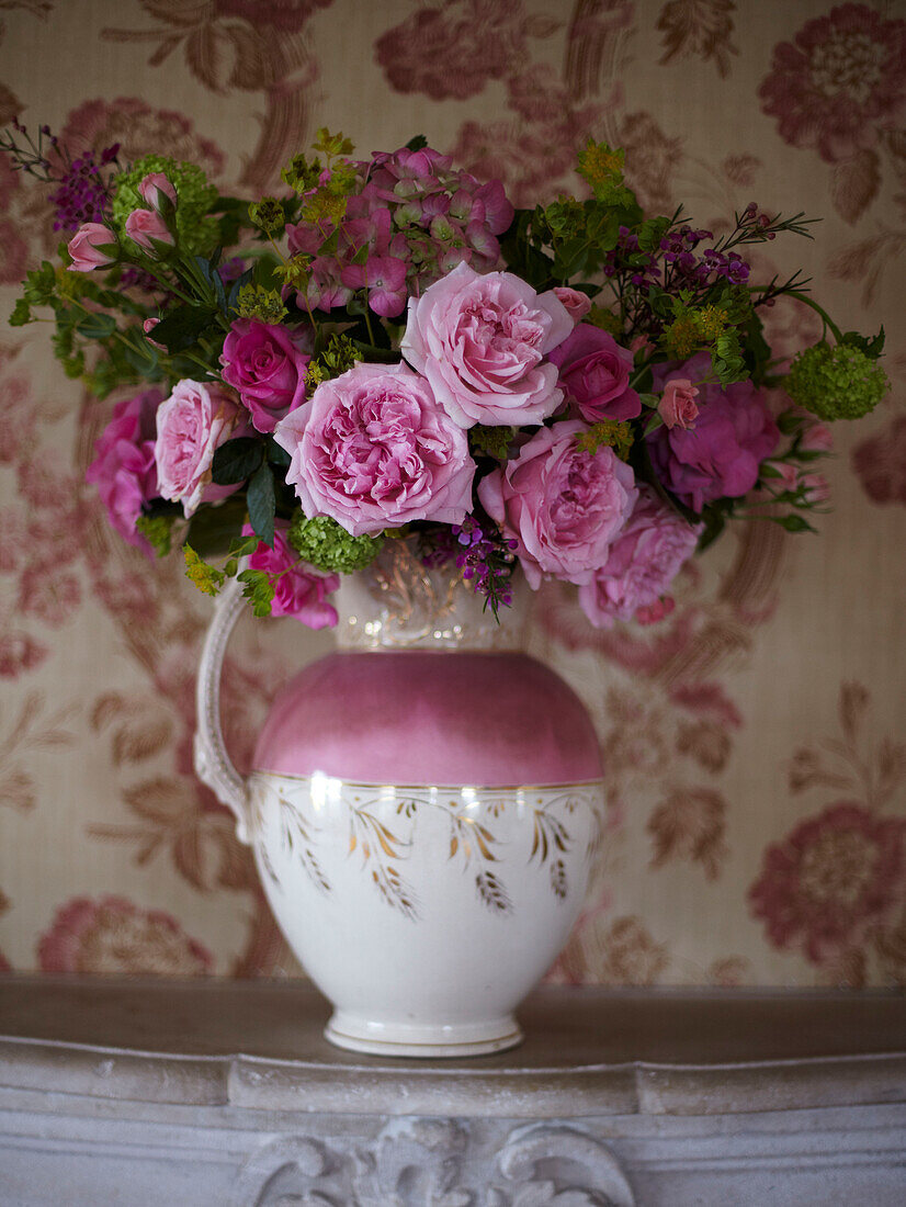 Vintage Blooms - Vase mit Schnittblumen in einem rosafarbenen Lüsterkrug auf einem Kaminsims