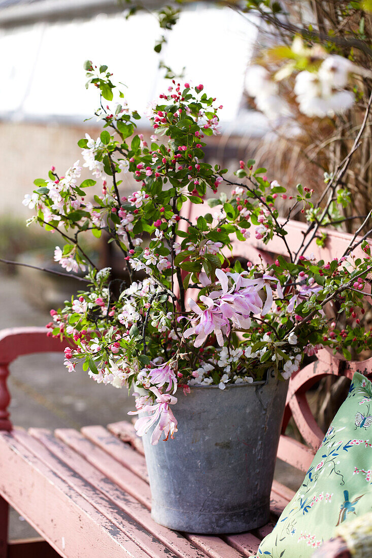 Outdoor spring floral decorations on pink painted garden bench in preparation for an Easter party