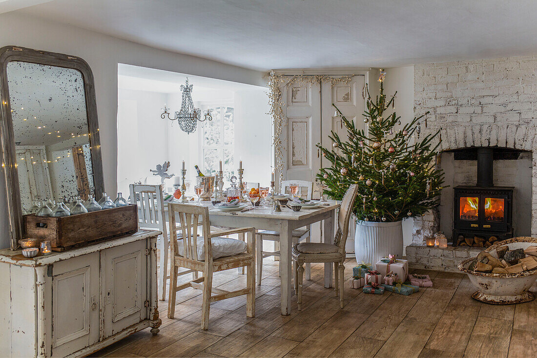 Festive table setting in dining room with decorated Christmas tree and lit candles