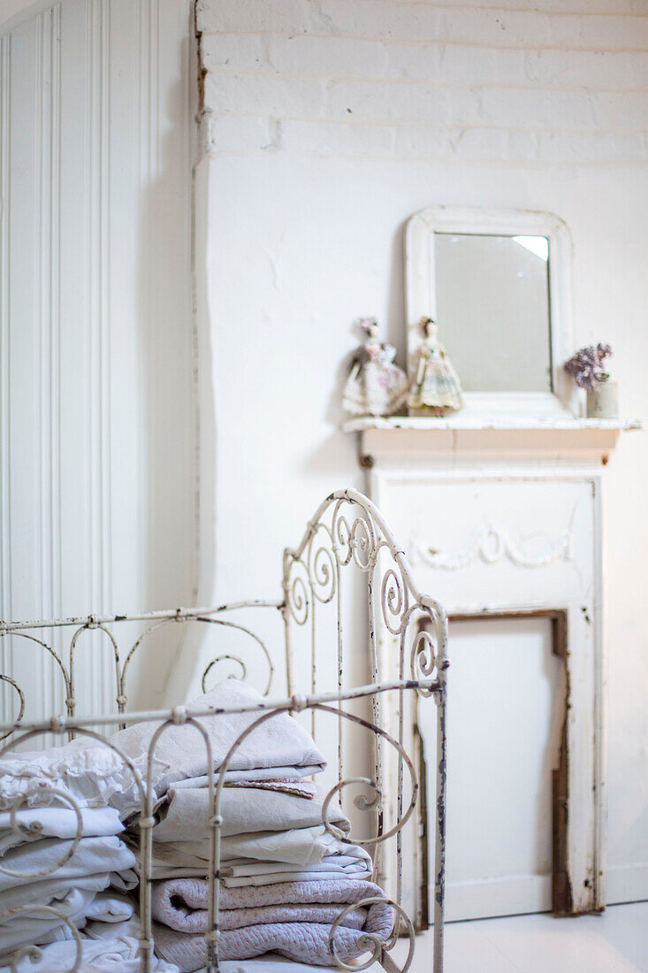 Vintage Wirework cot in white room with dolls above a painted fireplace