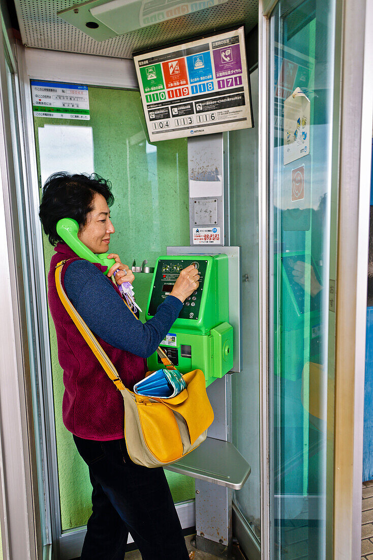 Woman using public payphone