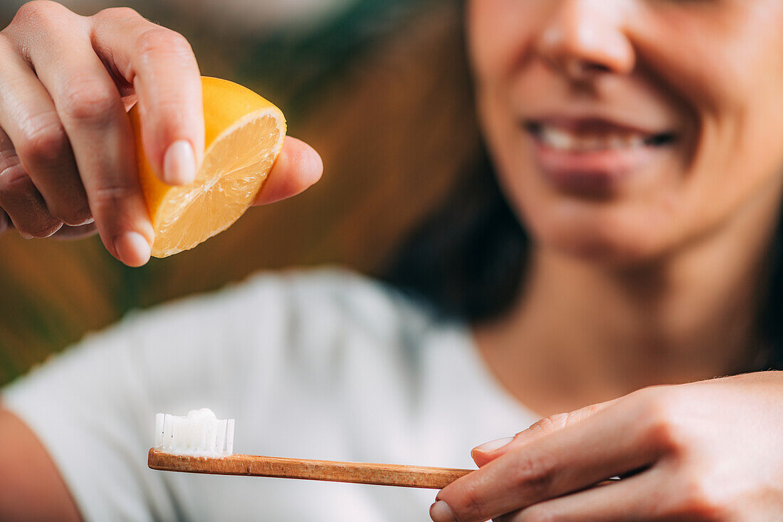 Woman squeezing lemon and baking soda mixture on toothbrush