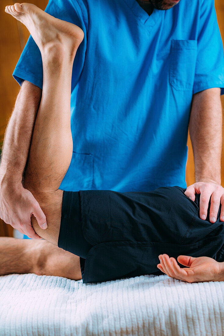 Physical therapist massaging injured leg of a male athlete