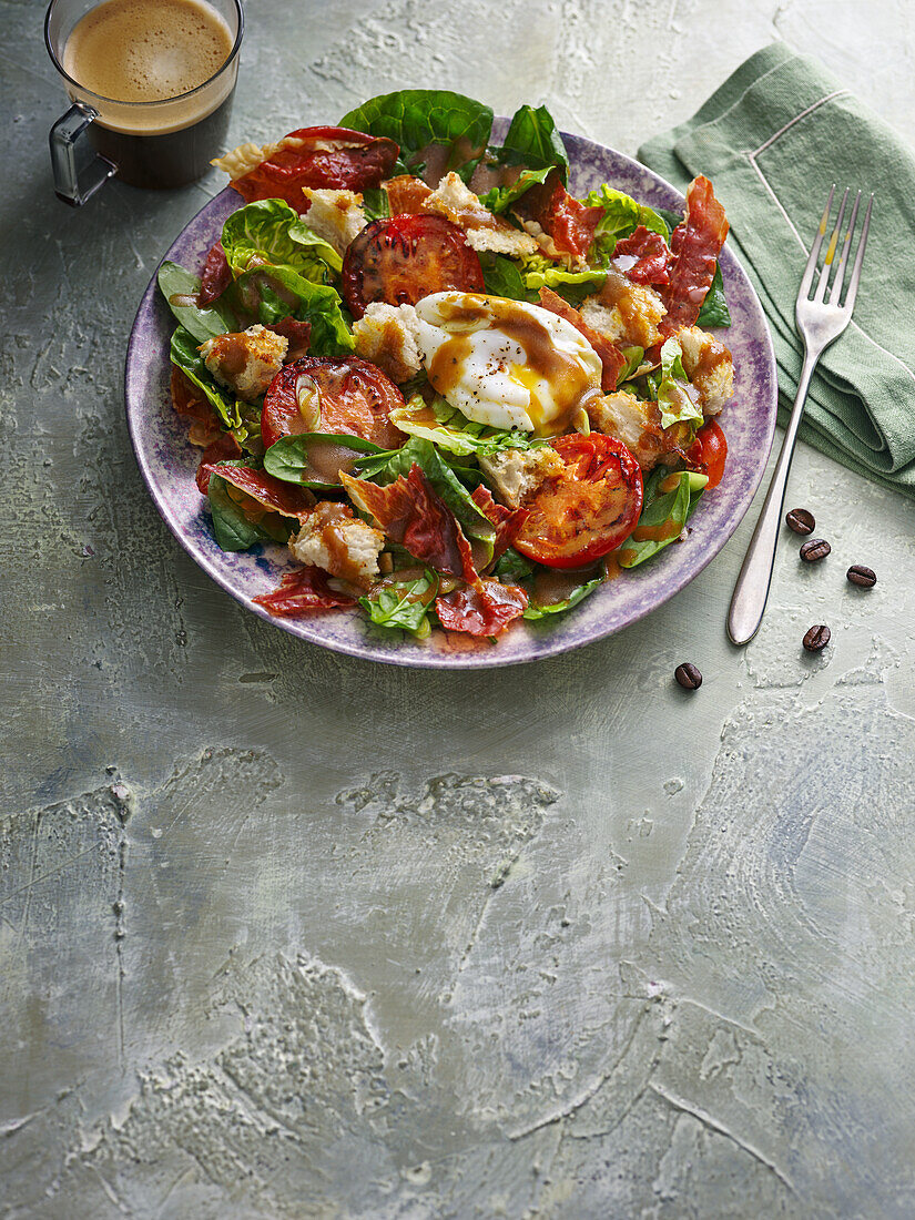 Brunch salad with tomatoes, bacon, poached egg, croutons and coffee dressing