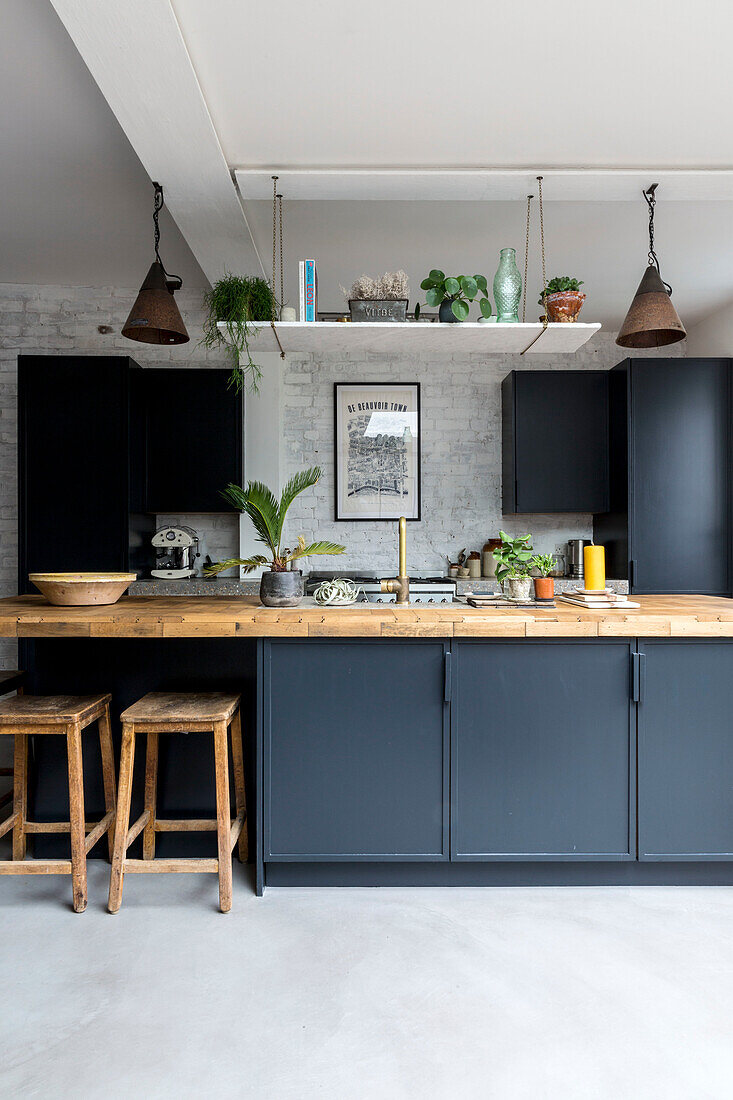 Moderne Küchenzeile in Schwarz mit Holzakzenten und diversen Zimmerpflanzen