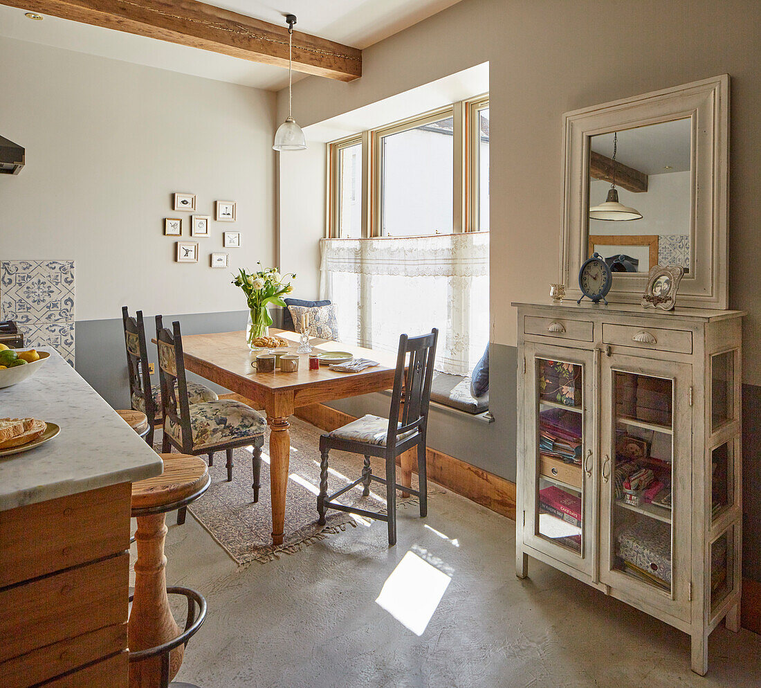 Cosy dining area with wooden table, seating area by the window and display cabinet