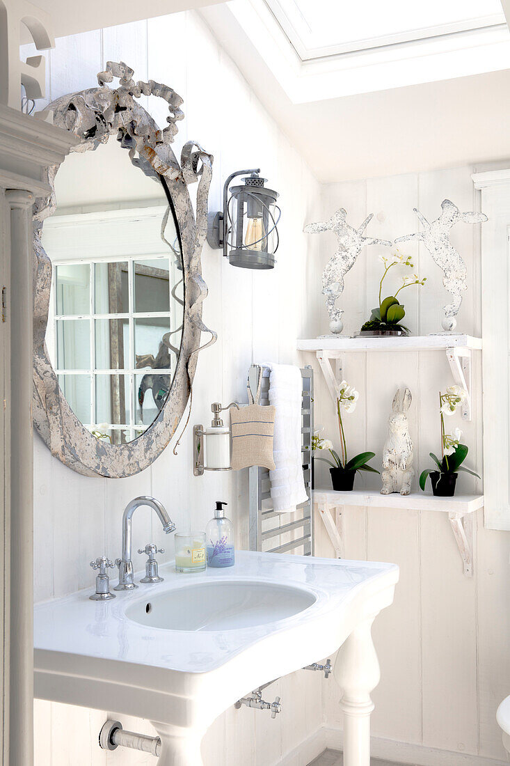 Bright wash area with mirror and orchids on a white shelf