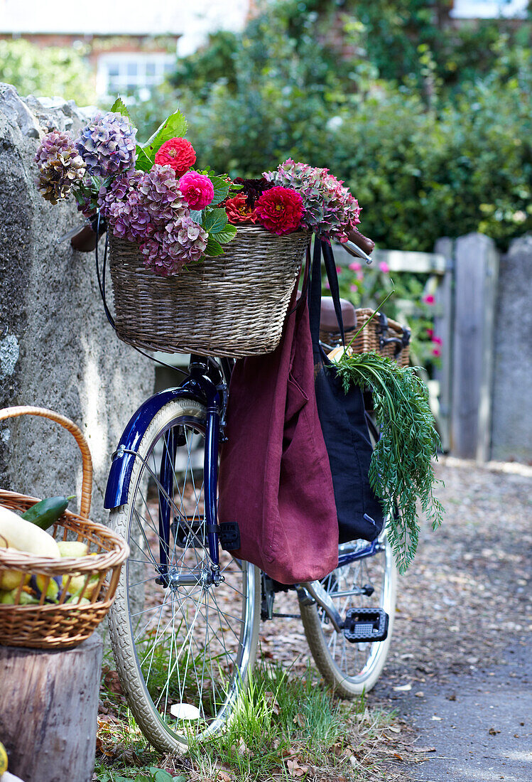 Bicycle with basket full of flowers and shopping bag against a stone wall