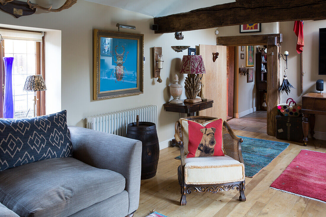 Cosy sofa and antique armchair with scatter cushions in rustic room