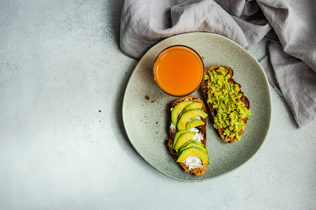 Healthy breakfast with avocado toasts on concrete table