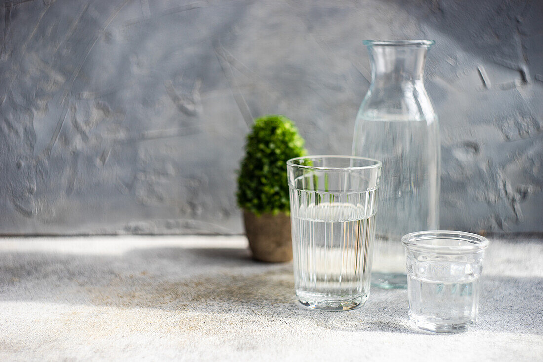 Healthy pure water in bottle and glasses on grey concrete table