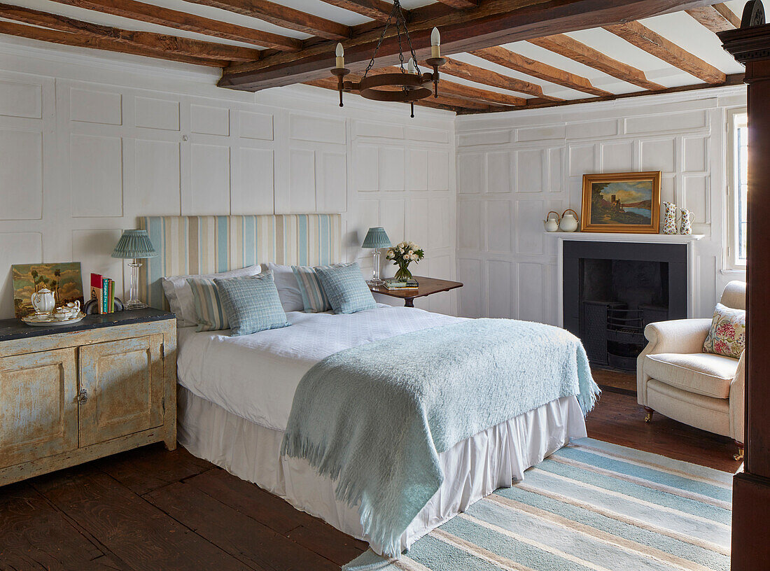 Queen bed, bedside cabinet and fireplace in a bedroom with coffered walls and exposed wood beamed ceiling
