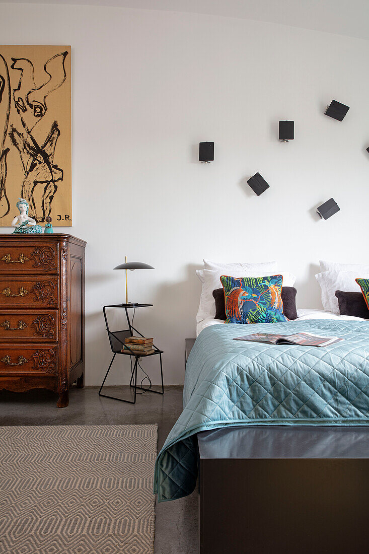 Doppelbett, darüber schwarze Leuchten an weißer Wand