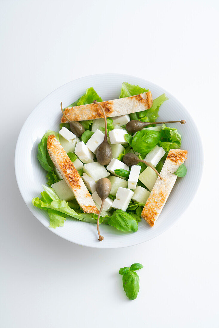 Salat aus weißer Melone, Feta und Kapern, mit Brotsticks