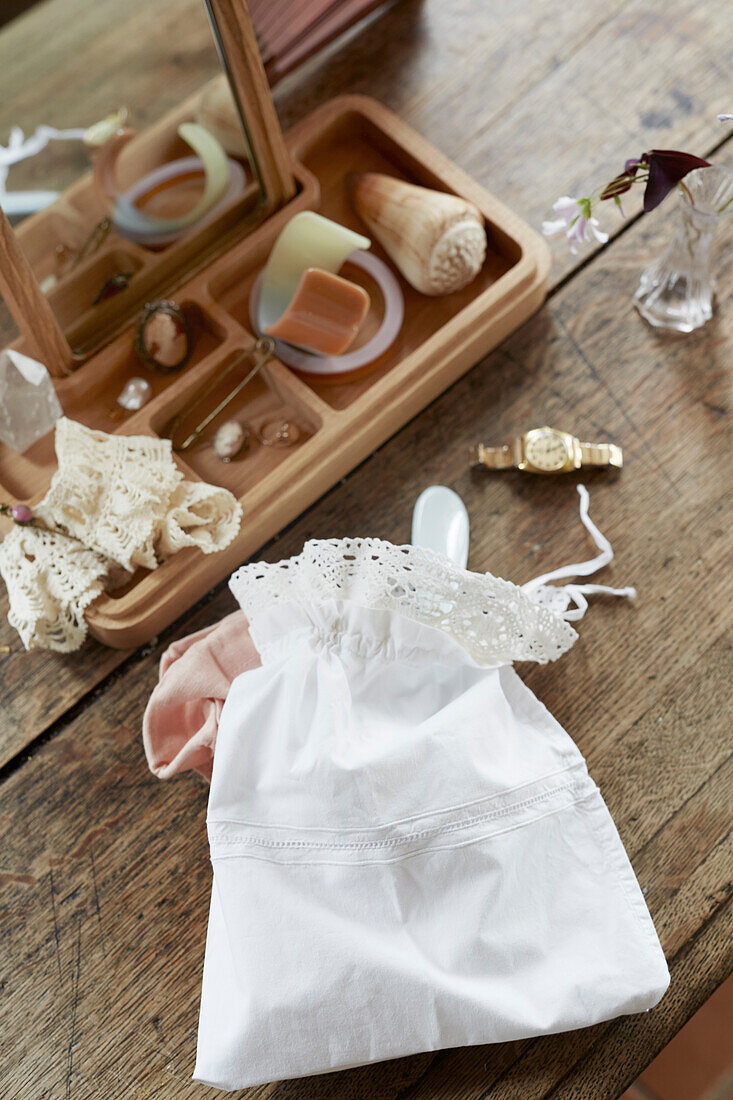 Fabric bag with decorative lace and storage with mirror on rustic wooden table