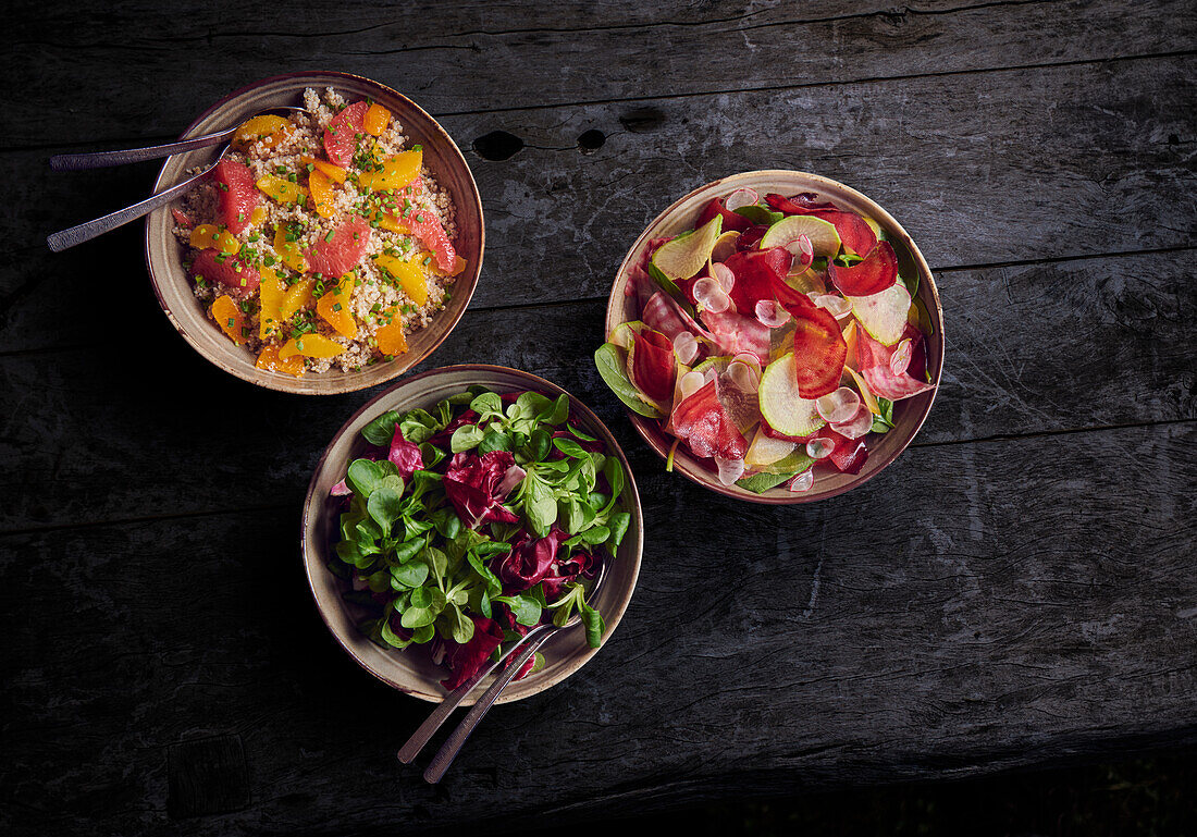 Drei verschiedene Salate (Bulgur, Rote-Bete und Feldsalat) auf Holztisch