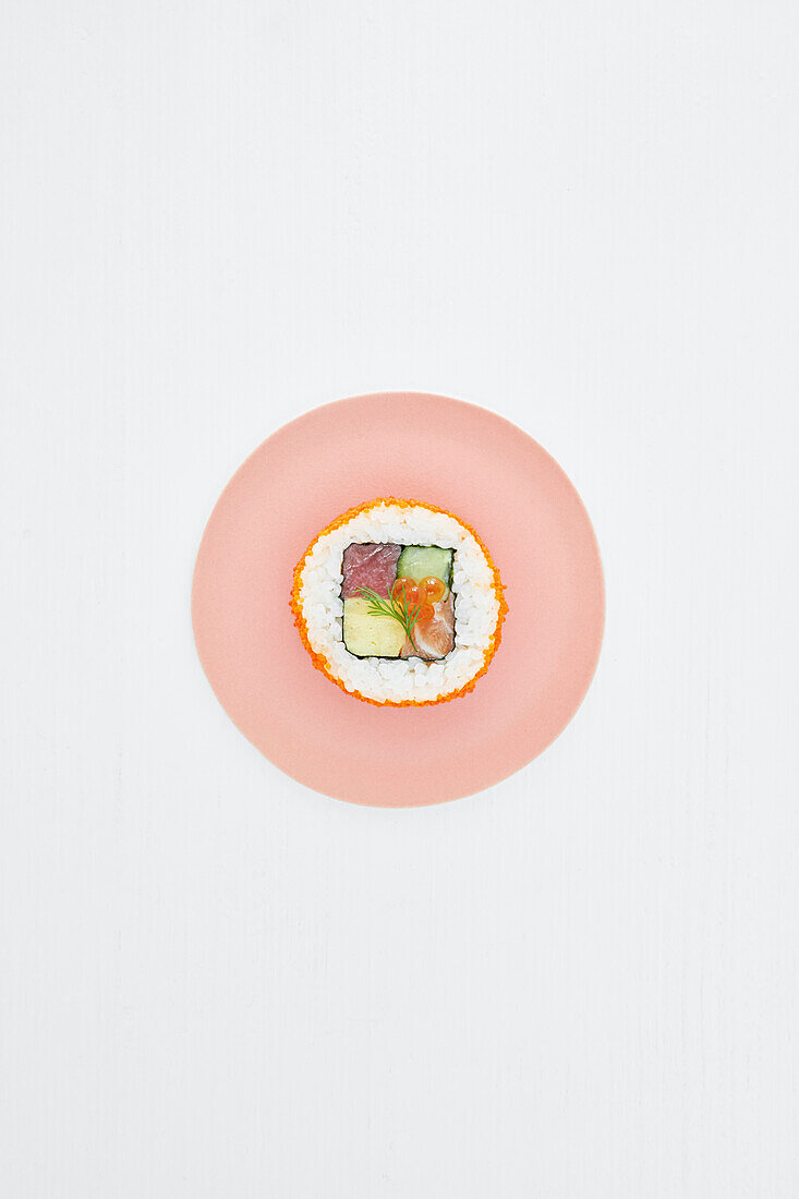 Eine Sushi Rolle auf rosa Teller