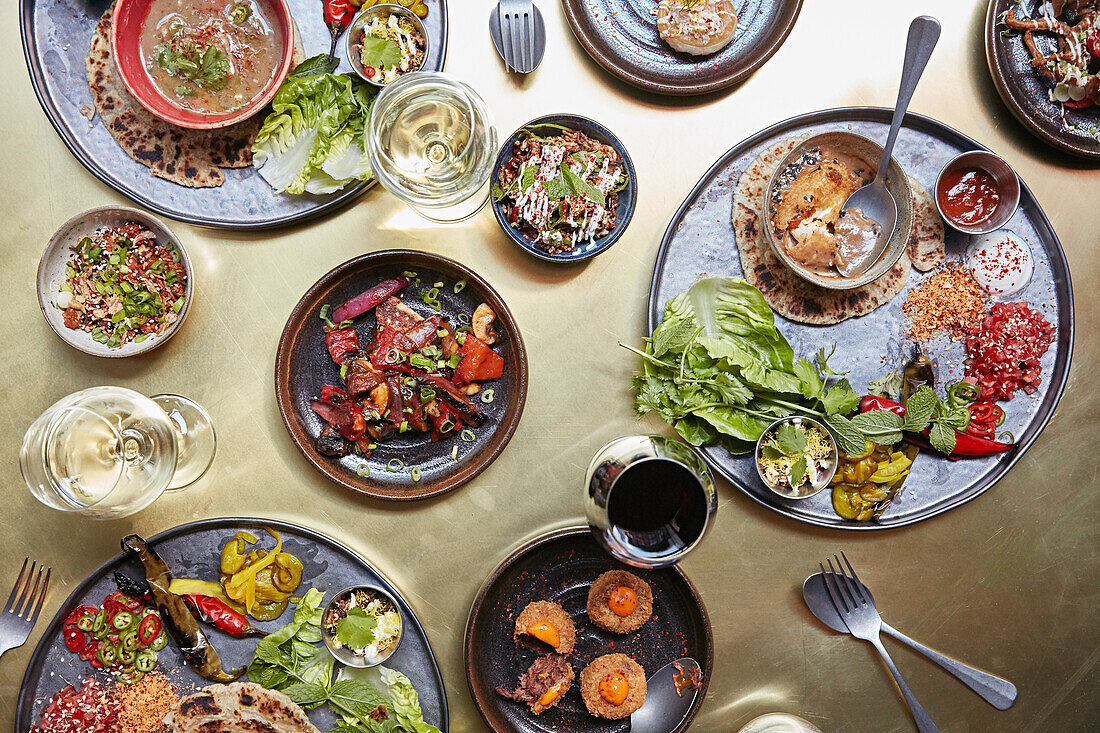 Food on a gold table laid out with several dishes and wine