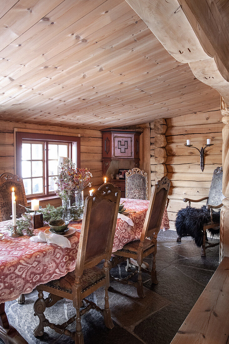 Rustikaler Essbereich in Blockhütte mit Kerzen und Blumenarrangement