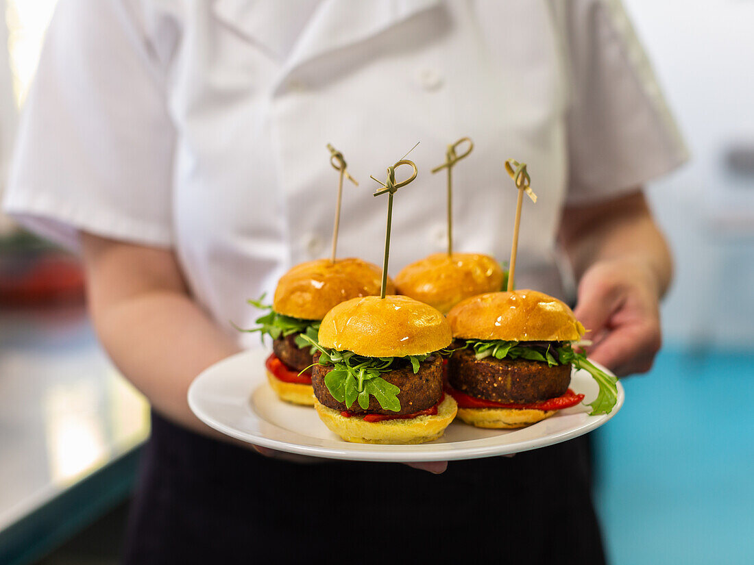 Waiter serves four mini veggie burgers