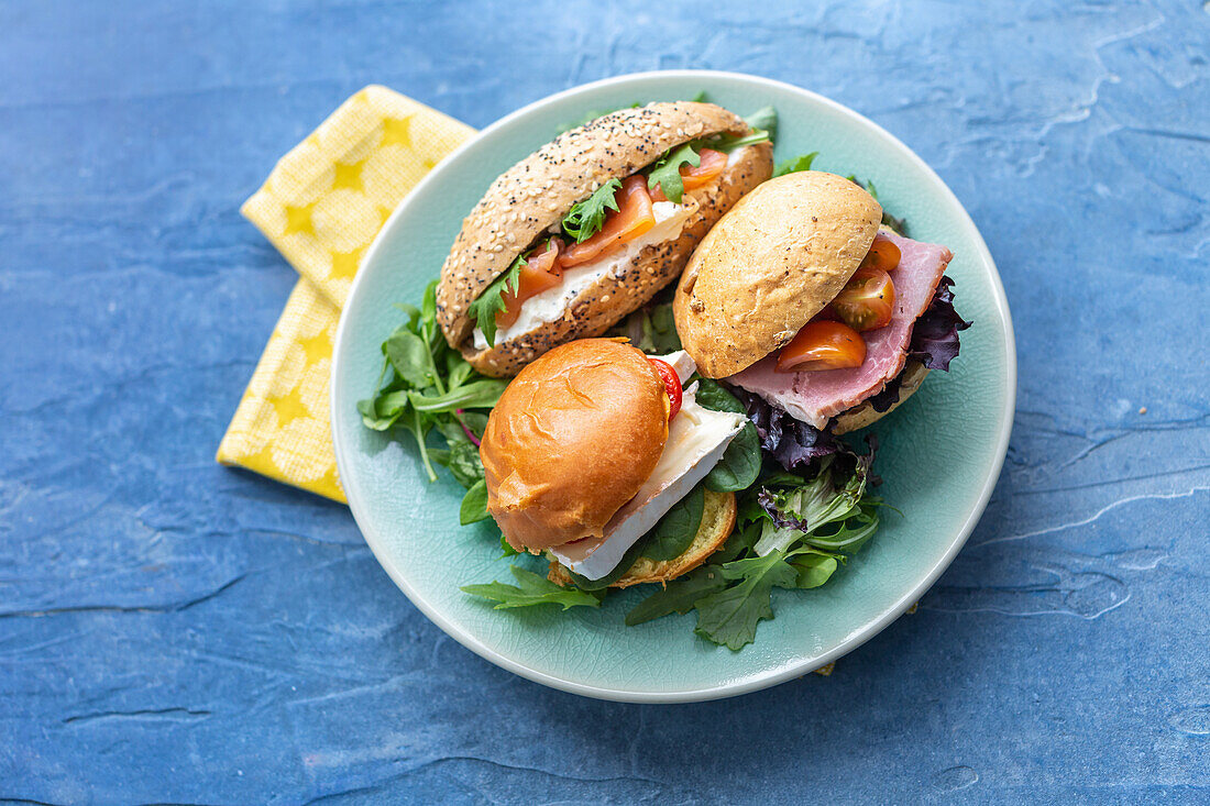 Sandwiches mit Brie, Räucherlachs und Schinken auf Blattsalat